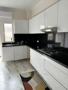 a kitchen with white cabinets and a stove top oven at Appartement lumineux et moderne sur Mohammedia in Mohammedia