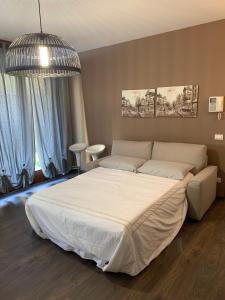 a bedroom with a large white bed and a chandelier at Xenia di Giò - Appartamento con giardino in Caravaggio
