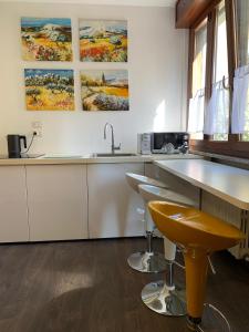 a kitchen with white cabinets and a sink and bar stools at Xenia di Giò - Appartamento con giardino in Caravaggio