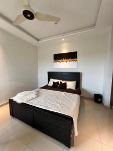 um quarto com uma cama grande e uma cabeceira preta em Modern 2 Bedroom Apartment with GYM&POOL em Lahore