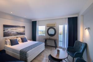 a bedroom with a bed and a chair and a mirror at Akti Hotel & Apartments in Mythimna
