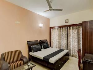 a bedroom with a bed and a chair at Super OYO Le Regent in Gurgaon