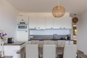 une cuisine avec des armoires blanches et une table et des chaises dans l'établissement Les Terrasses de l'Isolella - Vue mer et montagne, à Pietrosella 6 autres photos