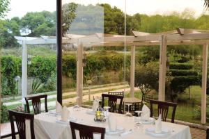 a table with white table cloth and chairs and a view of a garden at Hotel President in Golem