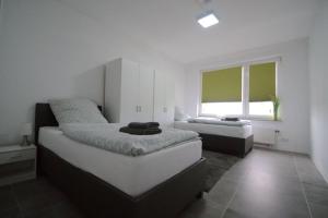 a white bedroom with two beds and a window at Frühlings Apartments GL21 in Bergisch Gladbach