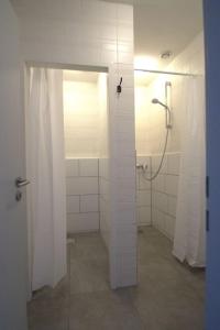 ein Bad mit einer Dusche und weißen Fliesenwänden in der Unterkunft Frühlings Apartments GL21 in Bergisch Gladbach