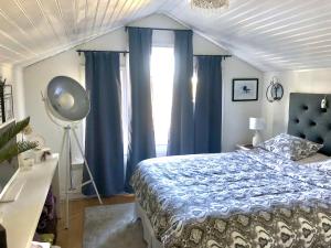 1 dormitorio con 1 cama con cortinas azules en Pleasant accommodation with its own beach located along the Jungfrukusten, en Bergby