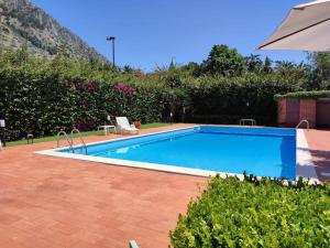a large blue swimming pool with an umbrella at Da Nonna Cettina Appartamento in villa con piscina in Palermo
