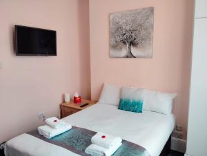 1 dormitorio con 2 camas y TV en la pared en United Lodge Hotel, en Londres