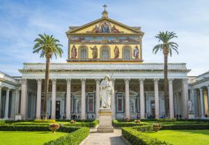 un edificio con una statua di fronte ad esso con palme di Erossuite GuestHouse a Roma