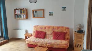 a living room with a couch with two red pillows at appartement chaleureux avec terrasse ensoleillée 2 étoiles in Le Mont-Dore