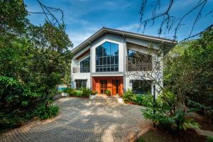an exterior view of a house with a driveway at SaffronStays Arabella in Alibaug