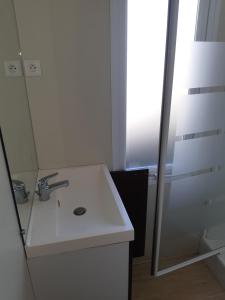 La salle de bains blanche est pourvue d'un lavabo et d'un miroir. dans l'établissement Mobile home S004, à Lancieux
