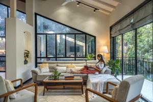 a woman sitting on a couch in a living room at SaffronStays Arabella - 4BR bohemian pool villa with sunken lounge, foosball, PS4 & mango orchard views in Alibaug in Alibaug