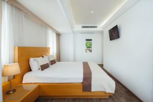 Schlafzimmer mit einem großen Bett mit einem Kopfteil aus Holz in der Unterkunft MB City Hotel in Izmir