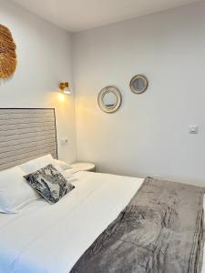 sypialnia z białym łóżkiem i 2 płytami na ścianie w obiekcie Apartamentos Val de Comillas w mieście Comillas