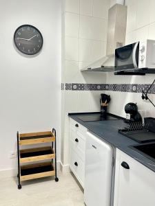 a kitchen with a clock on the wall and a counter at Apartamentos Val de Comillas in Comillas