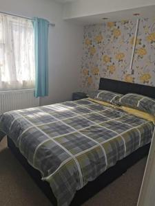 a bedroom with a bed with a plaid blanket on it at Fully refurbished holiday Chalet in withernsea in Withernsea
