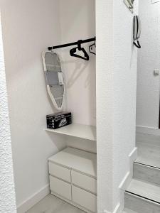 Apartamentos Val de Comillas في كوميلاس: غرفة خلع الملابس مع مرآة ورف