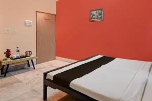 een bed in een kamer met een oranje muur bij OYO Florence Guest House And Home Stay in Calcutta