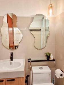 La salle de bains est pourvue de 2 miroirs, d'un lavabo et de toilettes. dans l'établissement Xavioré - Mesavirre Garden BCD, à Bacolod