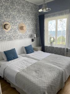 two beds in a bedroom with blue and white wallpaper at Nautic Hotell in Marstrand