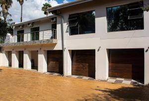 a white building with four garage doors and a balcony at Lux Lifestyle Forte’ in Johannesburg