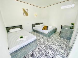 2 łóżka w pokoju z podłogą wyłożoną kafelkami w obiekcie เป็นต่อ รีสอร์ต w mieście Ban Kluk Faeb