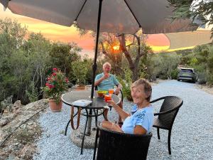 a man and a woman sitting at a table with an umbrella at Daphne Tiny House in Argalasti