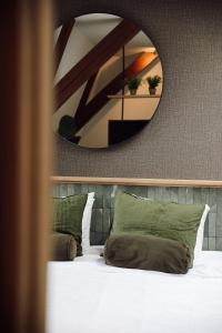 a large mirror above a bed with green pillows at Hotel Botanique Breda in Breda