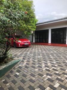 une voiture rouge garée devant une maison dans l'établissement Radiant Rooms, à Piliyandala