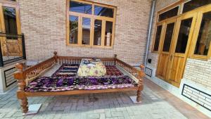 Un banco de madera con una colcha encima en un porche. en Guest House Muborak, en Samarkand