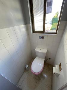 a small bathroom with a toilet with a pink lid at Hostel Marina in Nea Paphos
