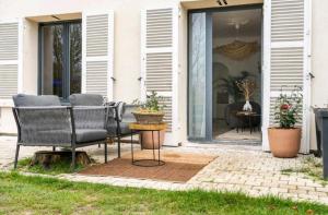 un patio con sillas y una mesa frente a una casa en Suite avec Jaccuzi, en Saintry-sur-Seine