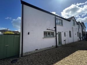 a large white building with a green garage at Coach House Annexe in Sandown