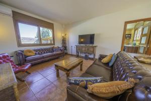 a living room with leather couches and a tv at HomeHolidaysRentals Karisma - Costa Barcelona in Argentona