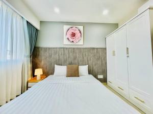 a bedroom with a white bed and a pink rose on the wall at Two Bedroom Happy Residence in Ho Chi Minh City