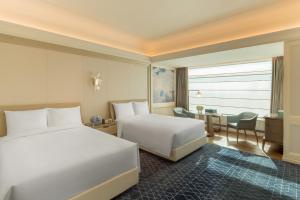 um quarto de hotel com duas camas e uma secretária em The Ritz-Carlton, Harbin em Harbin