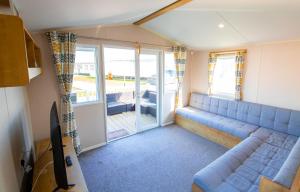 a living room with a blue couch and a sliding glass door at WW265 Camber Sands Holiday Park in Camber