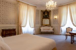 a bedroom with a bed and a chandelier at Hotel The Originals Château de Perigny in Vouillé