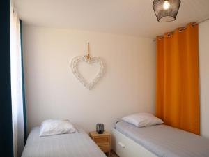 two beds in a room with a heart on the wall at Appartement spacieux pour 6 personnes in Saint-Omer