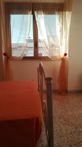 a bedroom with a bed and two windows with curtains at Casa RicAdri in Ginosa Marina