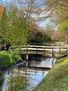 a wooden bridge over a river with a pond at Slapen op 77 in Nieuwe-Niedorp