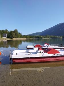 un barco rojo y blanco sentado en el agua en Camping Le Hameau Des Pécheurs, en Novalaise