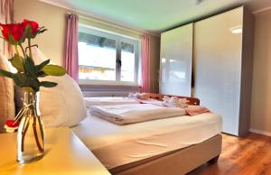 uma cama num quarto com um vaso de flores sobre uma mesa em Melanie - b51465 em Mittenwald