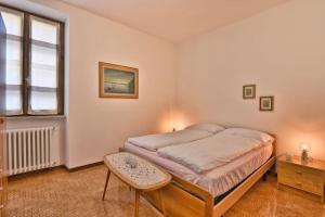 een slaapkamer met een bed met een tafel en een raam bij La Casa del Vento - Appartamento Lago - Rebomaholidays in Gargnano