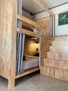 ein Etagenbett aus Holz in einem Zimmer mit Treppen in der Unterkunft Flora Hostel KhaoSok in Khao Sok