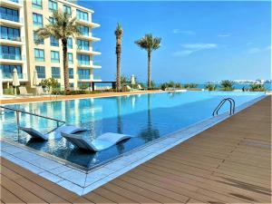 una piscina con 2 sillas y un edificio en Marassi shores - 310 en Durrat Al Bahrain