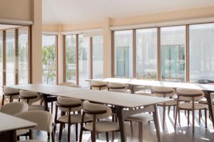 a row of tables and chairs in a room with windows at Emmarin Villa Pattaya in Nong Prue