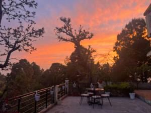 puesta de sol sobre un patio con mesa y sillas en The Umri Lansdowne, 4-bedroom homestay, en Lansdowne